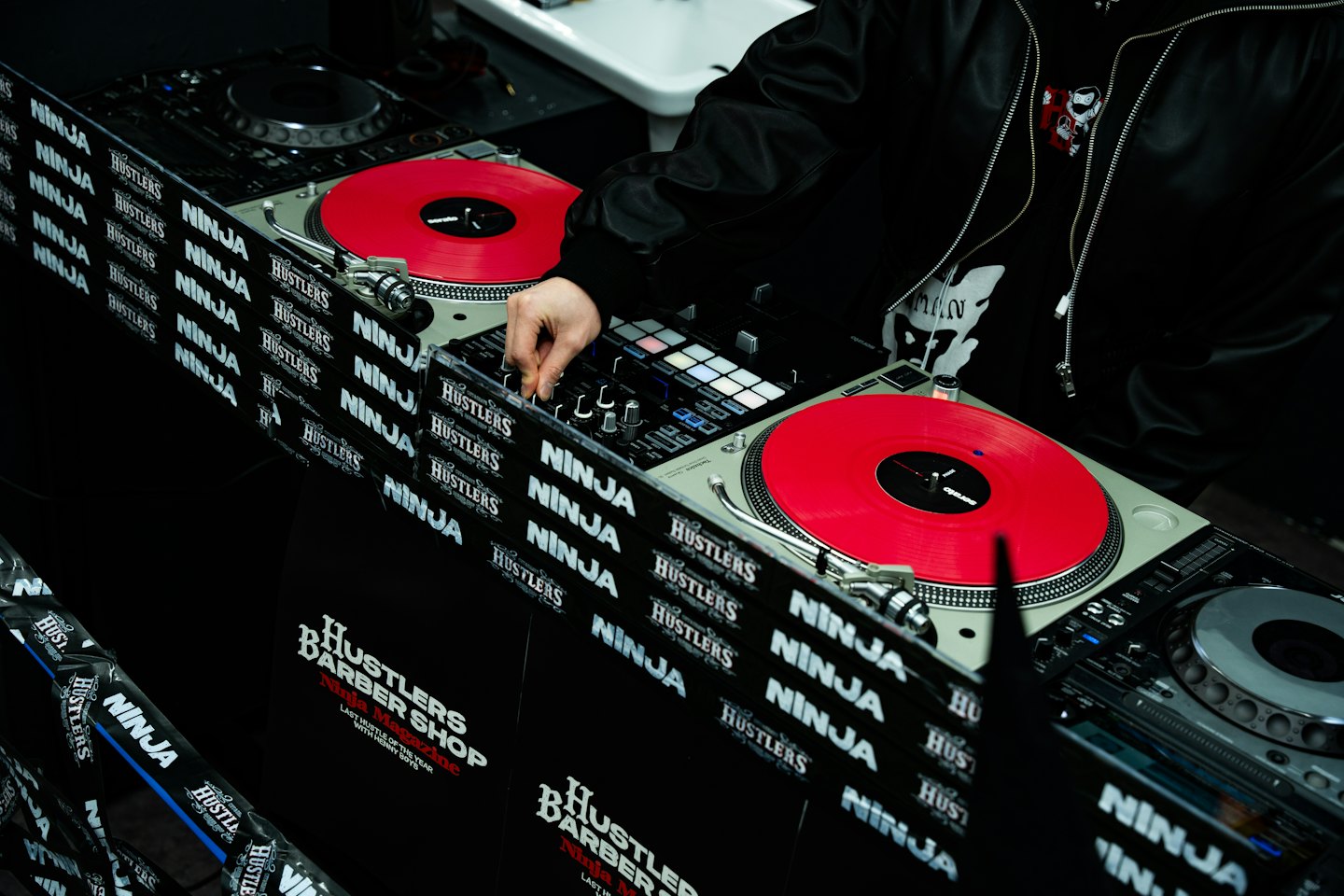 Dłonie regulujące sprzęt DJ-ski z czerwonymi płytami winylowymi.
